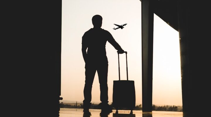 silhouette of man holding luggage inside airport